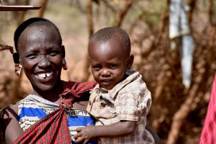 Lächelnde afrikanische Frau mit Kleinkind auf dem Arm