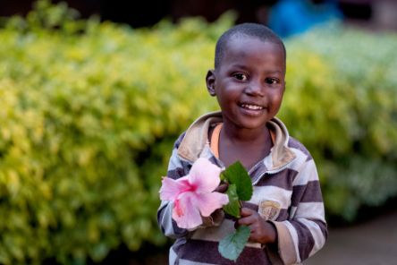 Ein kleines afrikanisches mädchen mit einer Blume in der Hand.