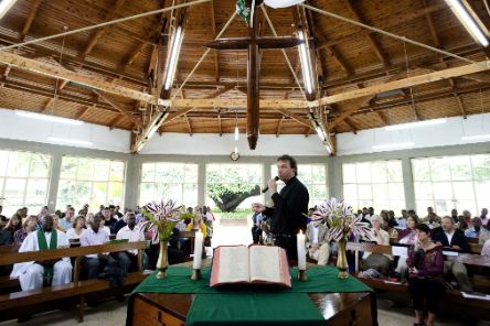 Ein Mann steht mit Mikrofon in einer Kirche hinter dem Altar. Finden Sie zahlreiche Ideen und Vorlagn für Ihren Gottesdienst.