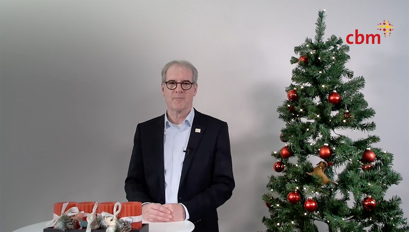 Dr. Rainer Brockhaus steht vor einem Tisch neben ihm ein Weihnachtsbaum.