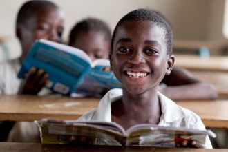 Lachender afrikanischer Junge mit Buch, Spenden für Kinder