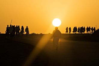 Menschen laufen im Sonnenuntergang eine Straße entlang.