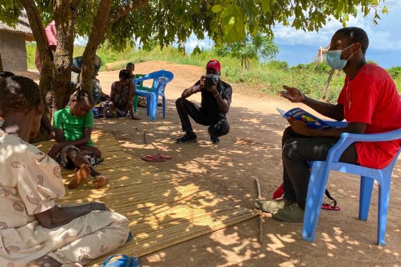 Zwei junge lachende afrikanische Männer, im Hintergrund ein Feld