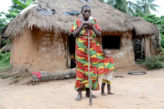 Eine afrikanische Frau und ein Kleinkind stehen vor einer Hütte